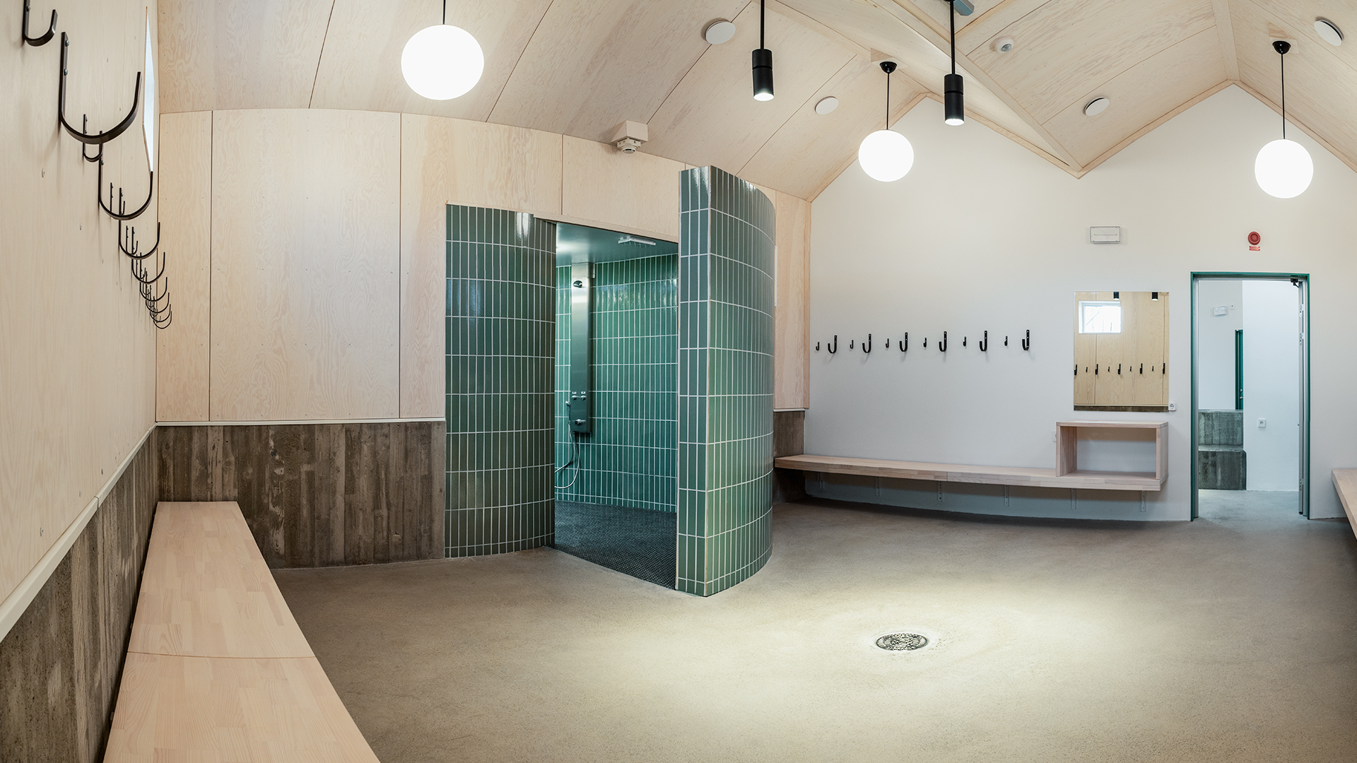 Omklädnings- och duschrum med klotformade takarmaturer och ett duschrum med väggar i runt utsnitt.