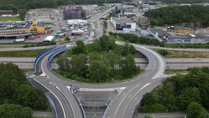 En körbana med gång- och cykelbana till vänster över en motorväg. Skyddsstaket längs vägen där den passerar över ett mot.