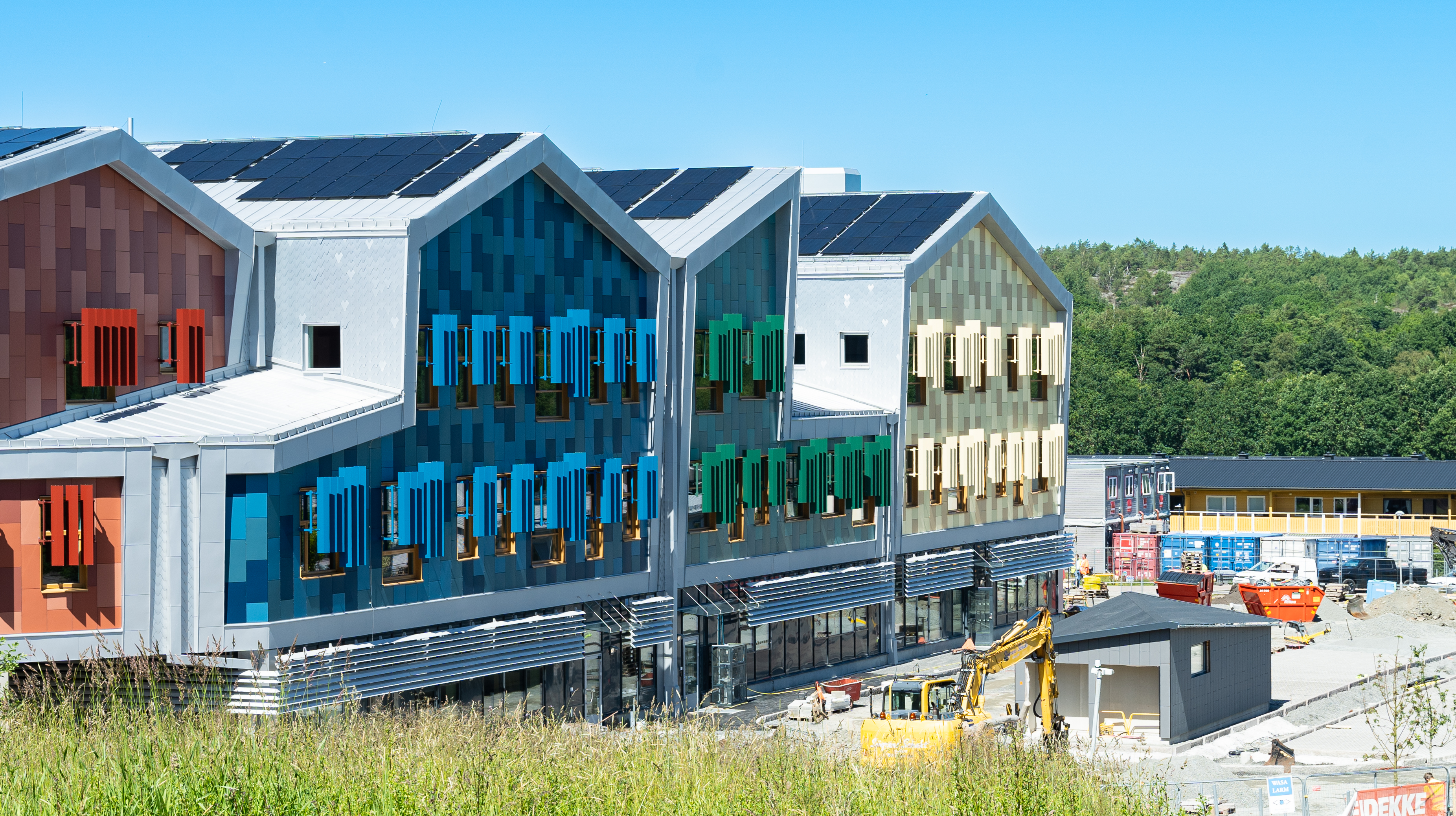 Skolan färgglad fasad syns i bakgrunden. 