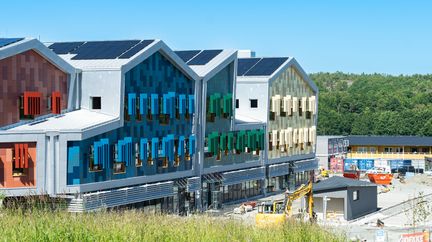 Skolan färgglad fasad syns i bakgrunden. 