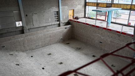 En tom bassäng helt i betong och en turkos trampolin.