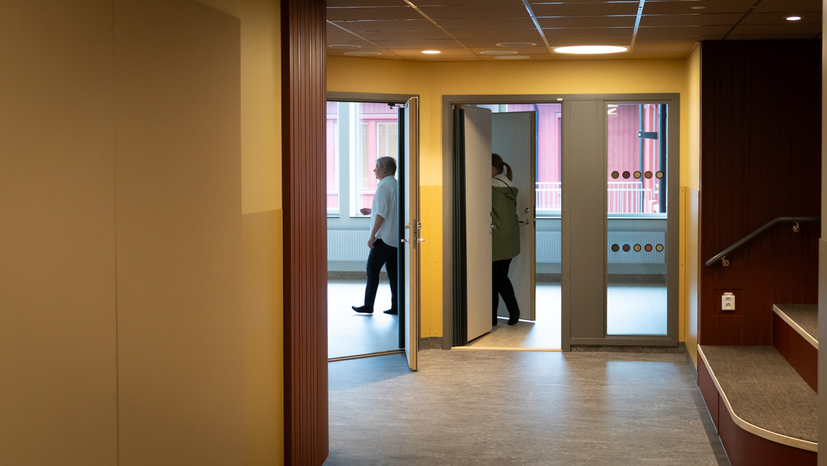 En hall i förgrunden med dörrar in till två klassrum längre bort i bilden.