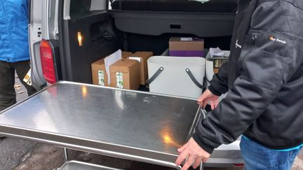 En person lastar in saker i en buss från en rullvagn.