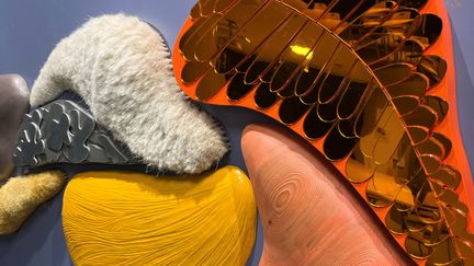 Närbild på ett taktilt konstverk med olika utstickande former i olika material.