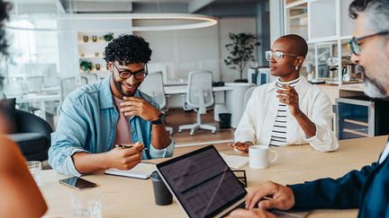 Ett pågående möte i ett mötesrum mellan några personer i ett öppet, ljust kontorslandskap.