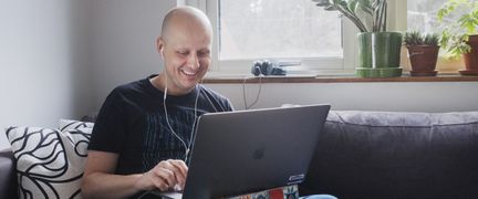Man sitter i soffan med en laptop i sitt knä.