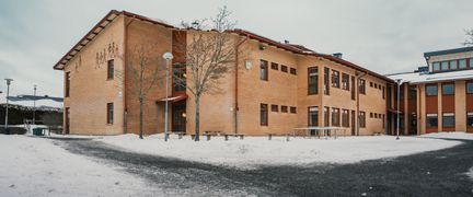 En av Klarebergsskolans byggnader med en skolgård och några bänkar i bakgrunden.