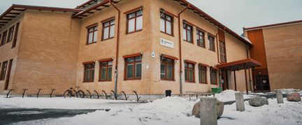 En av Klarebergsskolans byggander med skolans skylt i bakgrunden. En entré syns i bakgrunden.