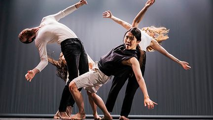 Fyra unga personer dansar på en scen. En kvinna i mitten böjer sig bakåt och tittar in i kameran