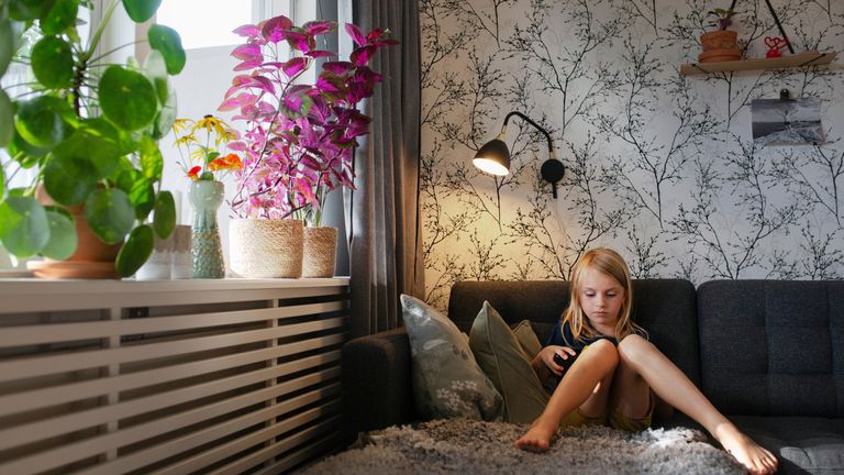 Ett barn har speltid i ett rum där lampan är tänd och elementet syns. 