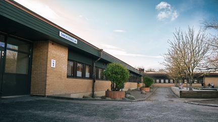 Önneredsskolans huvudbyggnad med skolgården och några växter i bakgrunden.