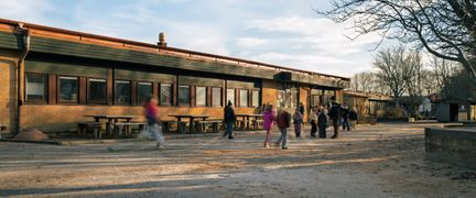 Önneredsskolans skolgård med några barn och bänkar i bakgrunden.