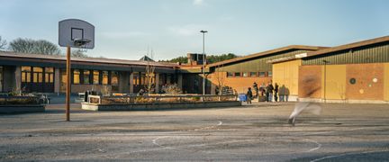 Önneredsskolans huvudbyggnad med skolgården och några barn i bakgrunden. En basketkorg syns i bilden.