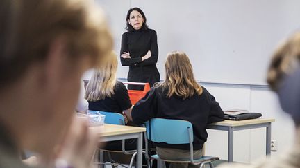 Lärare vid whiteboarden framför bänkrader med elever. 