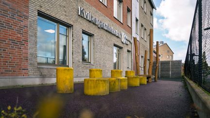  En rad gula pallar framför en skolbyggnad med texten Kvibergsnässkolan på fasaden.