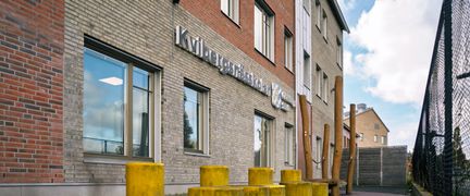  En rad gula pallar framför en skolbyggnad med texten Kvibergsnässkolan på fasaden.