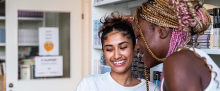 Two smiling students in the library.