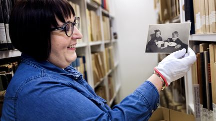 En medarbetare i ett arkivmagasin håller i ett foto