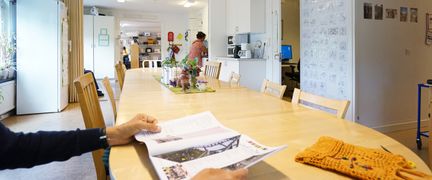 En person läser en tidning i ett stort ljust kök.