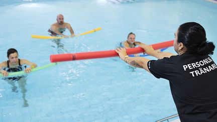 Gruppträning i vatten. Tre personer följer en instruktör.