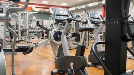 Gymmet i Askims simhall med träningscyklar i förgrunden, många olika maskiner och fria vikter i bakgrunden.