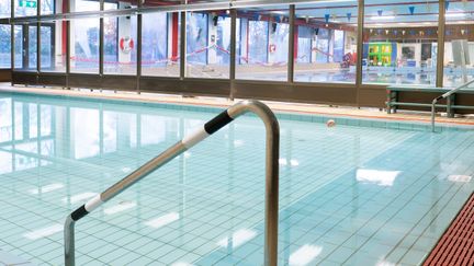 Bassäng med stilla vatten. I bakgrunden syns glasfönster och en till bassäng bakom.