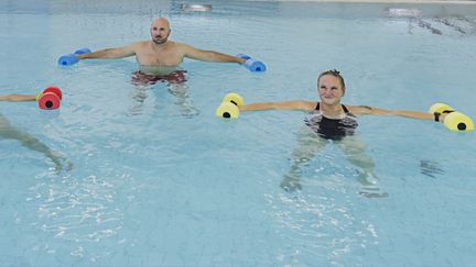 Tre personer som deltar i gruppträningspass i vatten.