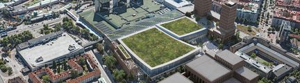 Flygbild över arenakomplex med grästak och höghus