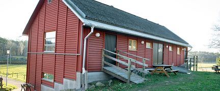 Ett rött hus med gröna hagar bakom.