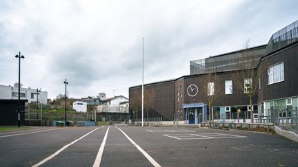 Långedragsskolans skolgård med några bänkar och träd i bakgrunden.