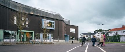 En skolgård med några elever framför Långedragsskolan.