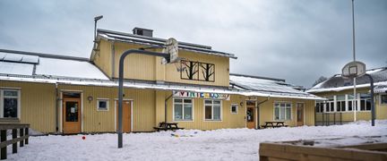 Kärrdalsskolans huvudbyggnad med några basketkorgar och bänkar i bakgrunden.