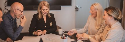  Foto på personer som sitter och samtalar över ett stort papper vid ett bord på ett kontor