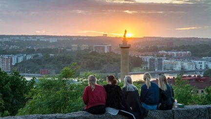 Fem ungdomar sitter och blickar ut över en solnedgång i Göteborg.