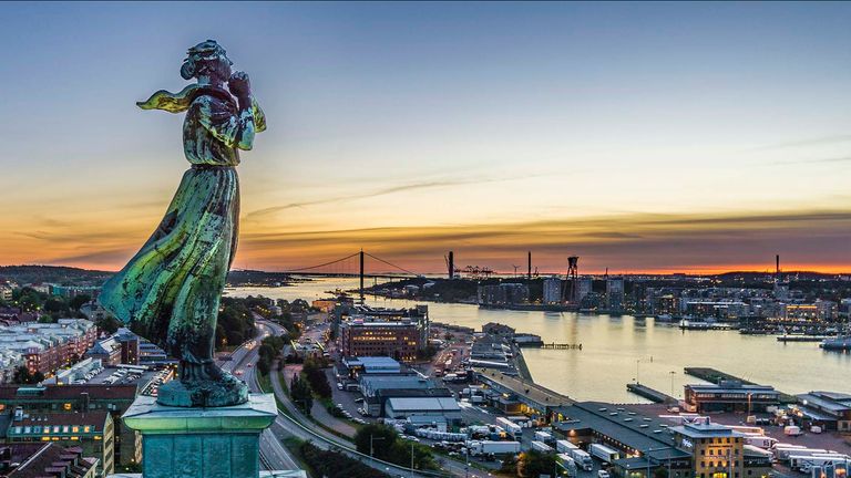 Flygbild över Göteborg i skymning med statyn sjömanshustrun i förgrunden.