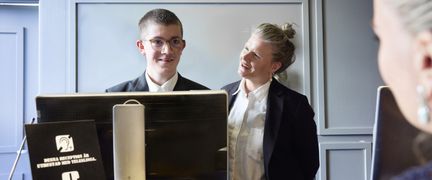 En elev och lärare står bakom en receptionsdisk. 