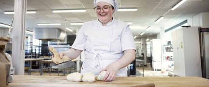 En elev står vid ett bakbord och delar upp en deg.