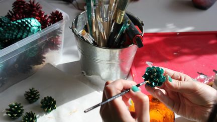 En person målar kottar i olika färger.