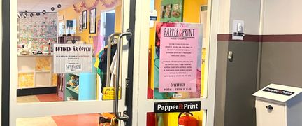 En glasdörr med texten Papper och print och utanför sitter en brevlåda.