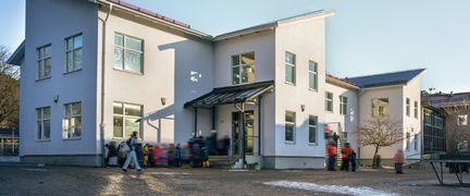 En grupp elever som står utanför en vit skolbyggnad.