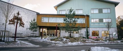 En skolbyggnad med texten Härlandatjärnskolan på fasaden med några bänkar framför sig. 