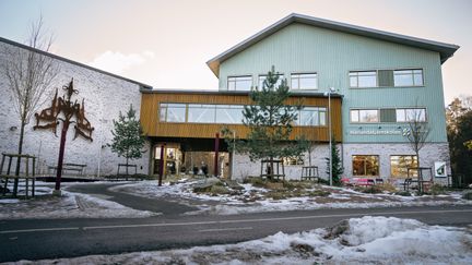 En skolbyggnad med texten Härlandatjärnskolan på fasaden med en väg framför.