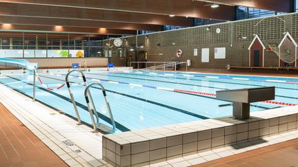 Bassängen i Kärra simhall sedd från ett hörn. I förgrunden syns en plint och handtag till trappan ner i bassängen. Vattnet är stilla.