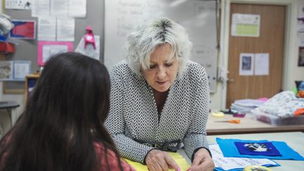 Ett foto av en pedagog som visar en elev något på en gul tygbit.