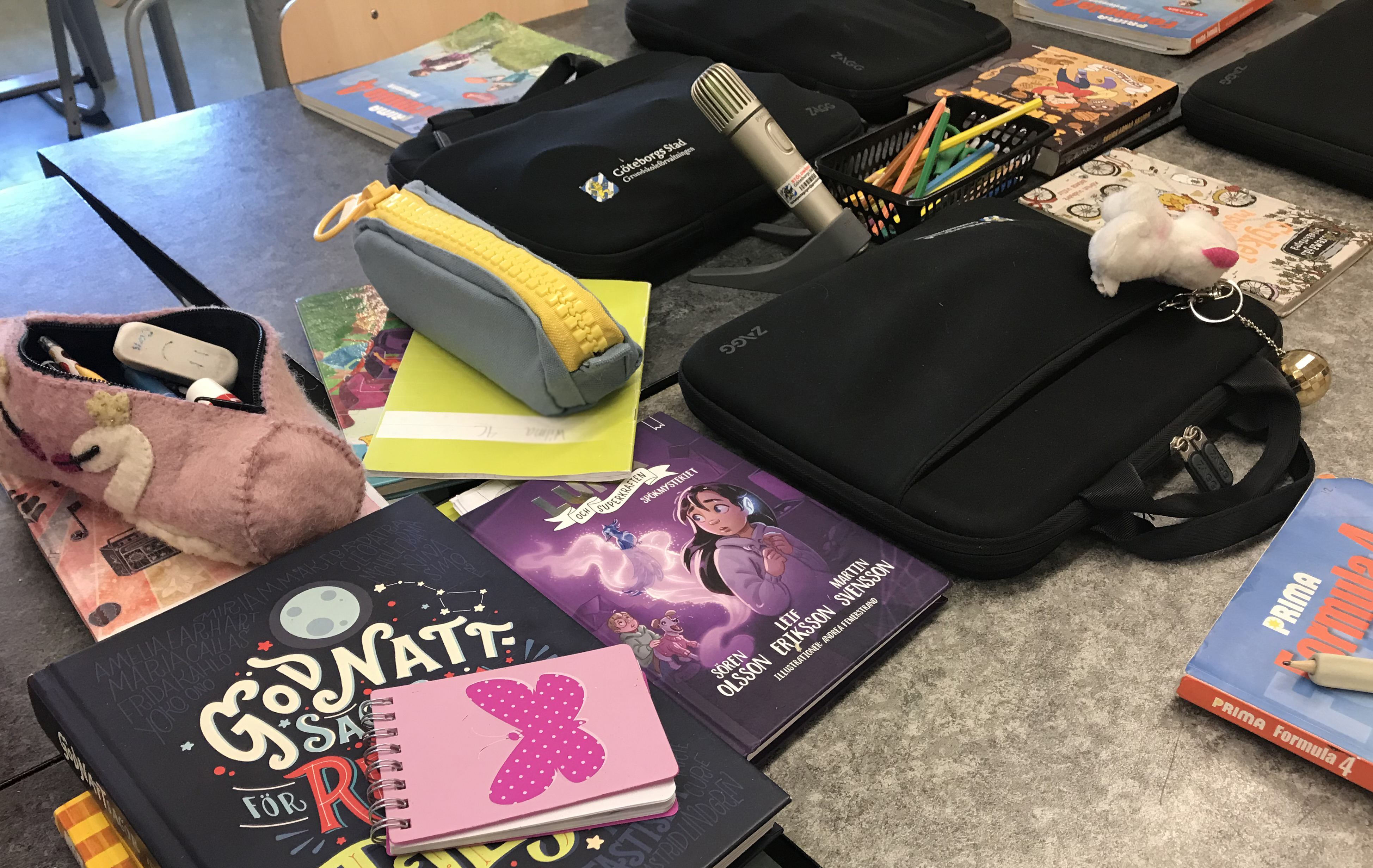 Bilden visar en skolbänk med böcker och en mikrofon