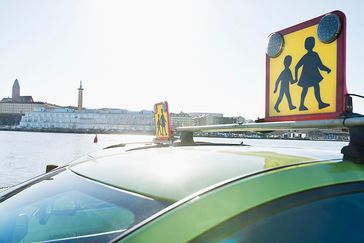 En grön taxibil med en skolskjuts skylt