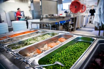 Skolkök med stora serveringskärl fyllda med grönsaker