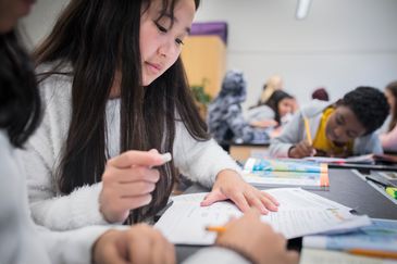 Elever sitter i ett klassrum vid sina skolbänkar och arbetar.