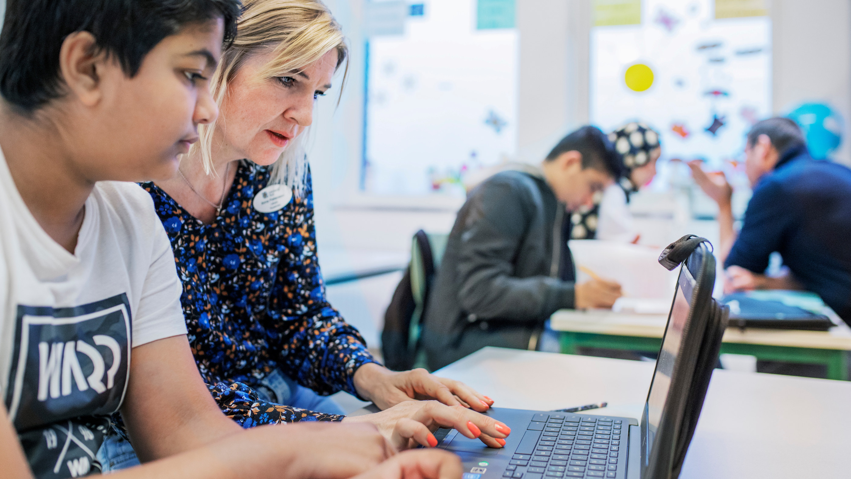 Elev och lärare sitter framför en datorskärm i ett klassrum