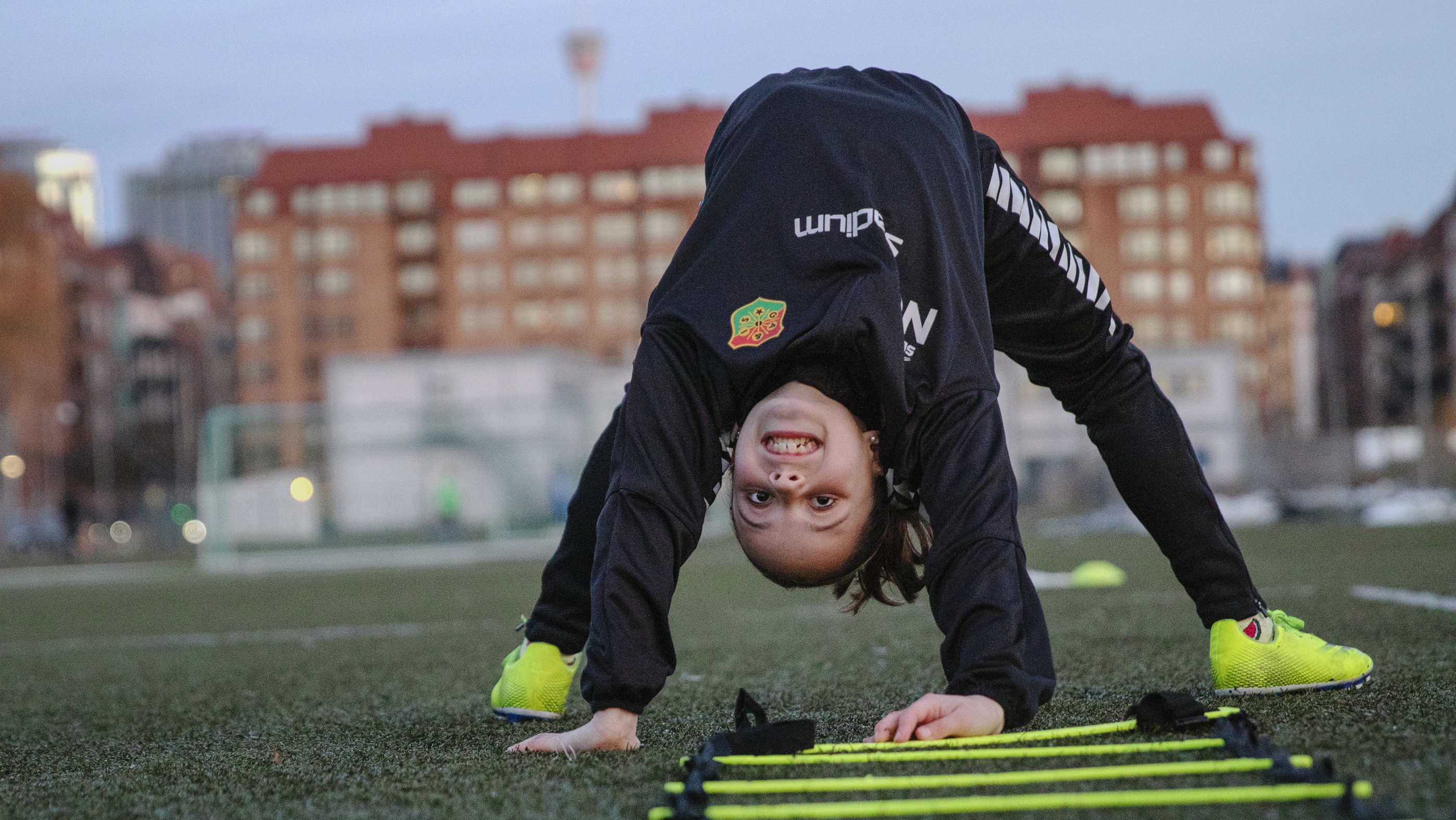 Ett barn står brygga på en fotbollsplan.